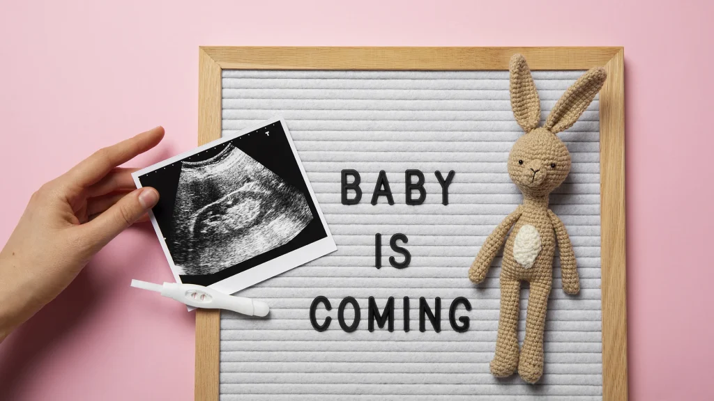 Pizarra que pone "Baby is coming" con juguete de bebe y una ecografía
